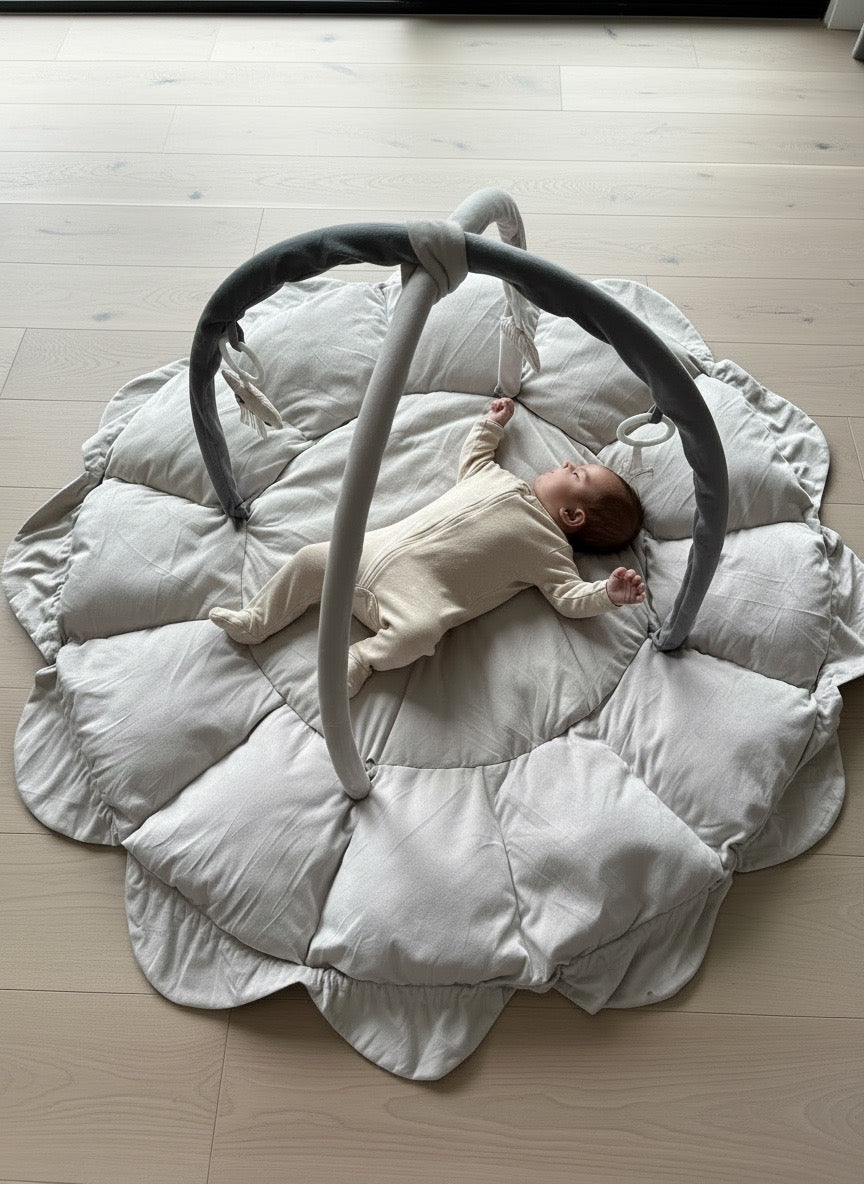 Baby lying on a Lumee Novi play gym with hanging toy mobile