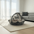 Baby play gym on a rug in a living room with a sofa and curtains.